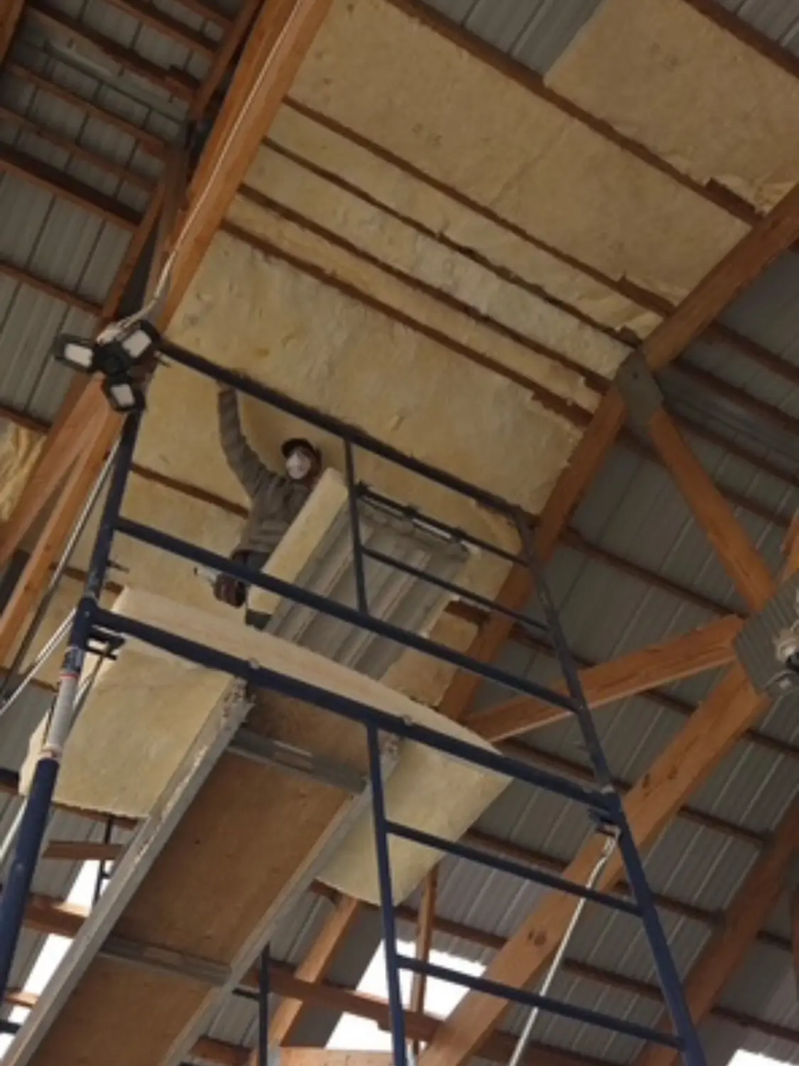 Radiant barrier contractor installing reflective insulation in a Denver metal building