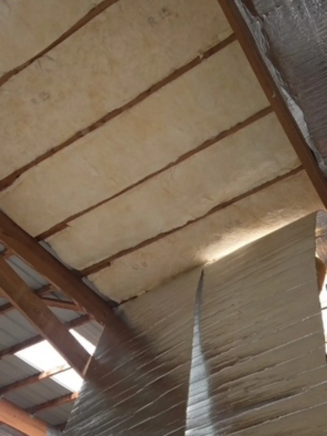 Contractor installing radiant barrier foil insulation along attic rafters